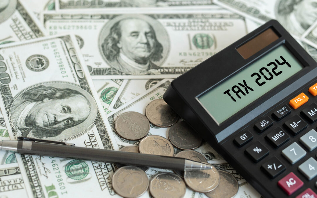 A stack of money next to a calculator displaying 'Tax 2024'.